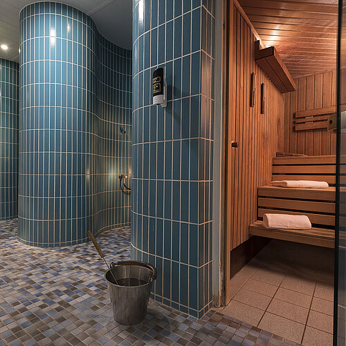 Sauna area in the Maritim proArte Hotel Berlin with traditional wooden sauna benches, blue tiles and modern showers.