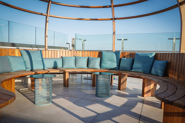 Round terrace seating with wooden bench and blue cushions at Maritim Hotel Amelia