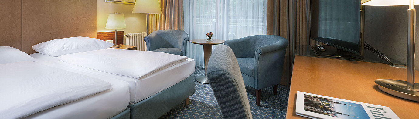 Comfortable double room at Maritim Hotel Fulda with modern furnishings, desk, and cozy seating area.