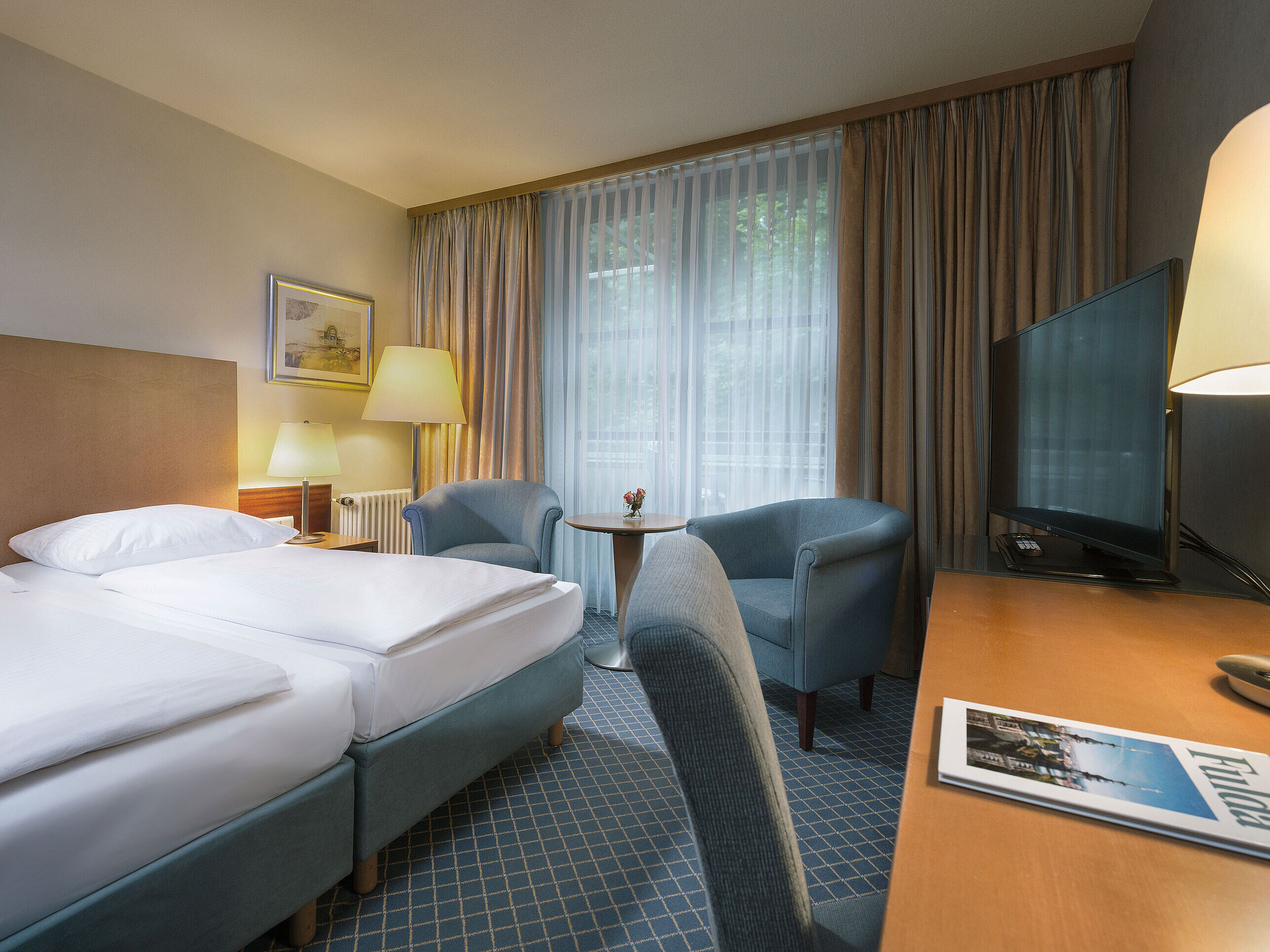 Comfortable double room at Maritim Hotel Fulda with modern furnishings, desk, and cozy seating area.