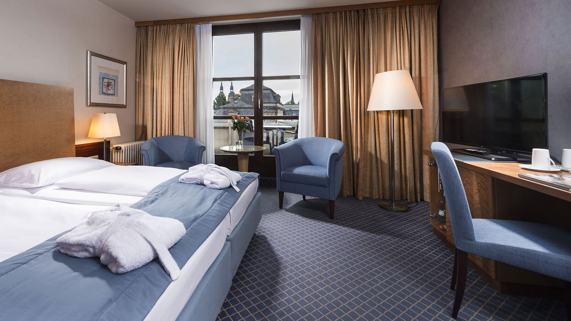 Elegant superior room at Maritim Hotel Fulda with double bed, seating area, and balcony overlooking the city.