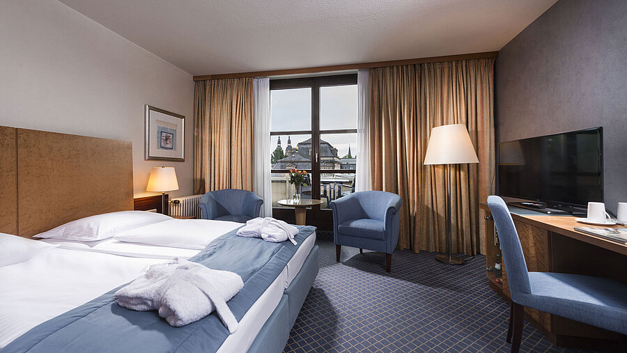 Elegant superior room at Maritim Hotel Fulda with double bed, seating area, and balcony overlooking the city.