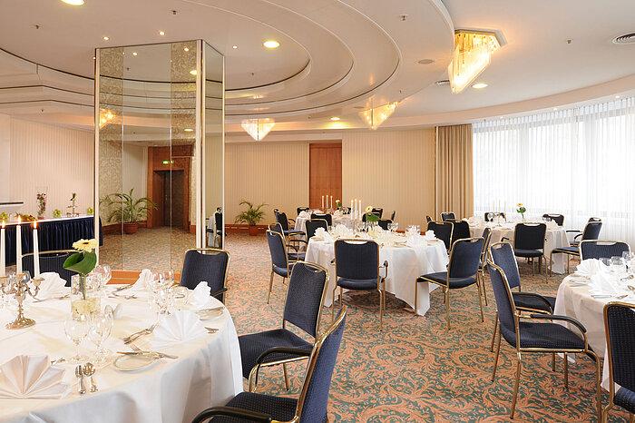 Salon Dresden at Maritim Hotel Magdeburg with elegantly set white-clothed tables, candelabras, and stylish lighting for festive events.
