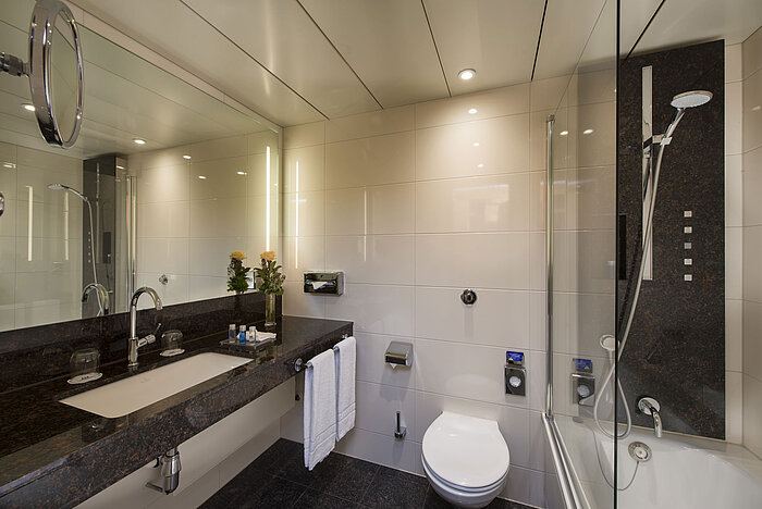 Spacious bathroom with shower, toilet, mirror and granite sink at the Maritim Hotel Stuttgart