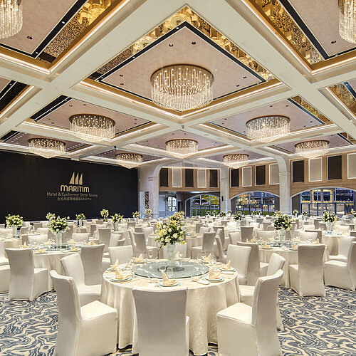 Elegant Maritim Hotel banquet hall with round tables, white décor and floral centrepieces