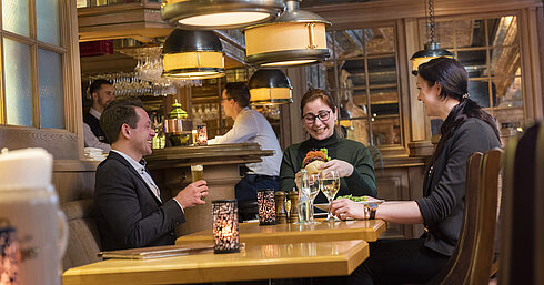Guests enjoying a meal and drinks in the cozy ambiance of the "Kölsche Stuff" beer and wine tavern.