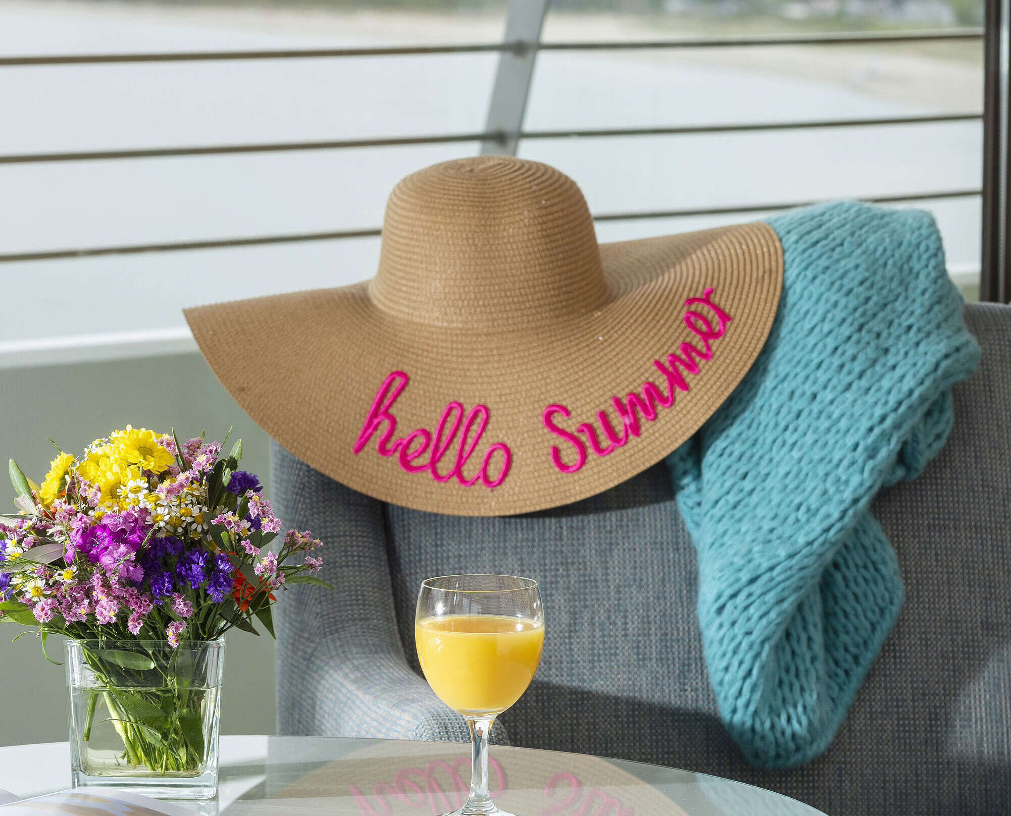 Detail with sun hat, blanket and juice glass by the window overlooking the Baltic Sea