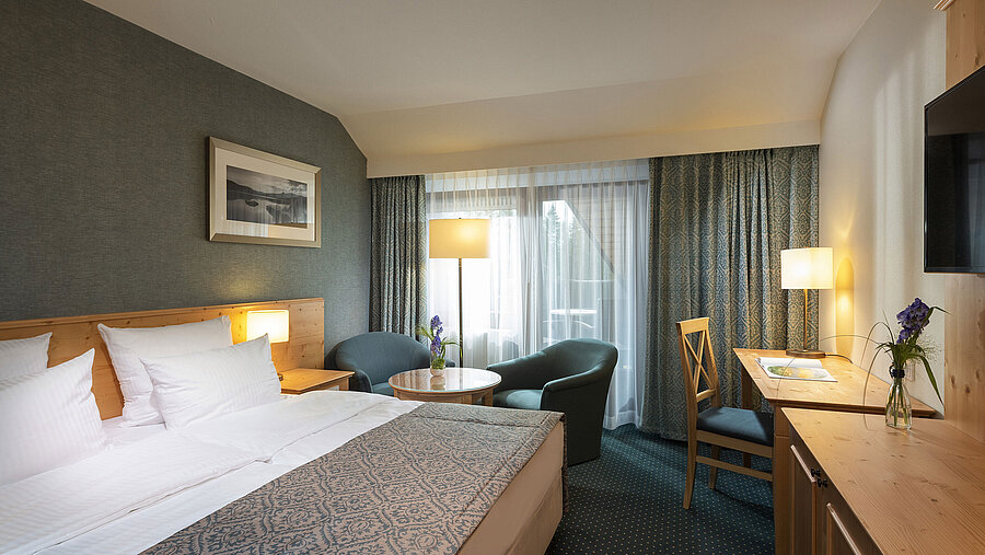 Cosy double room with desk and seating area at Maritim Hotel Titisee