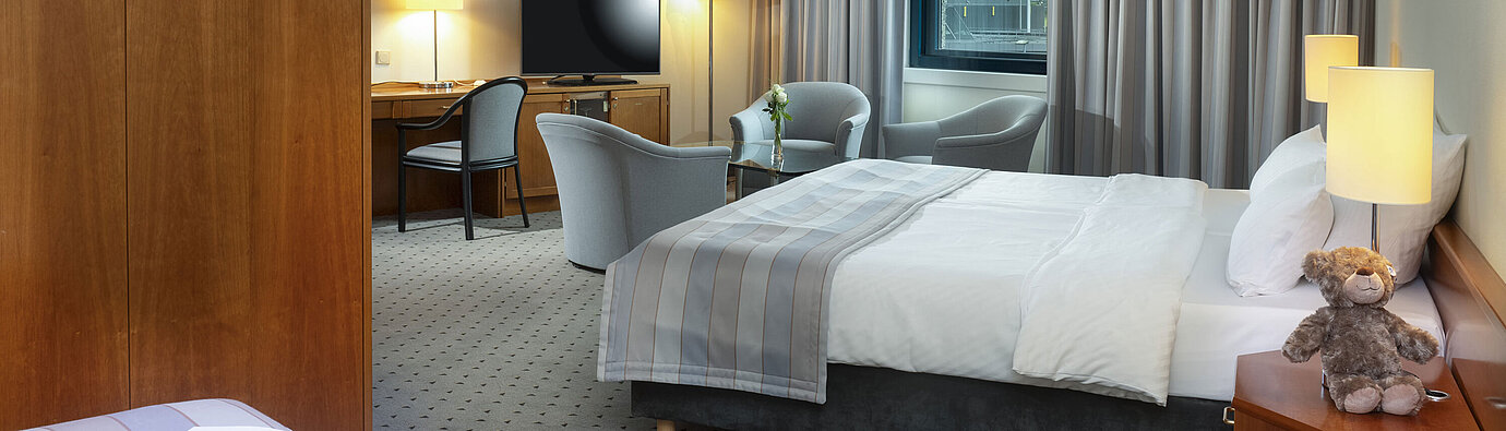 Spacious family room with double bed, seating area, and airport view at Maritim Hotel Hannover.