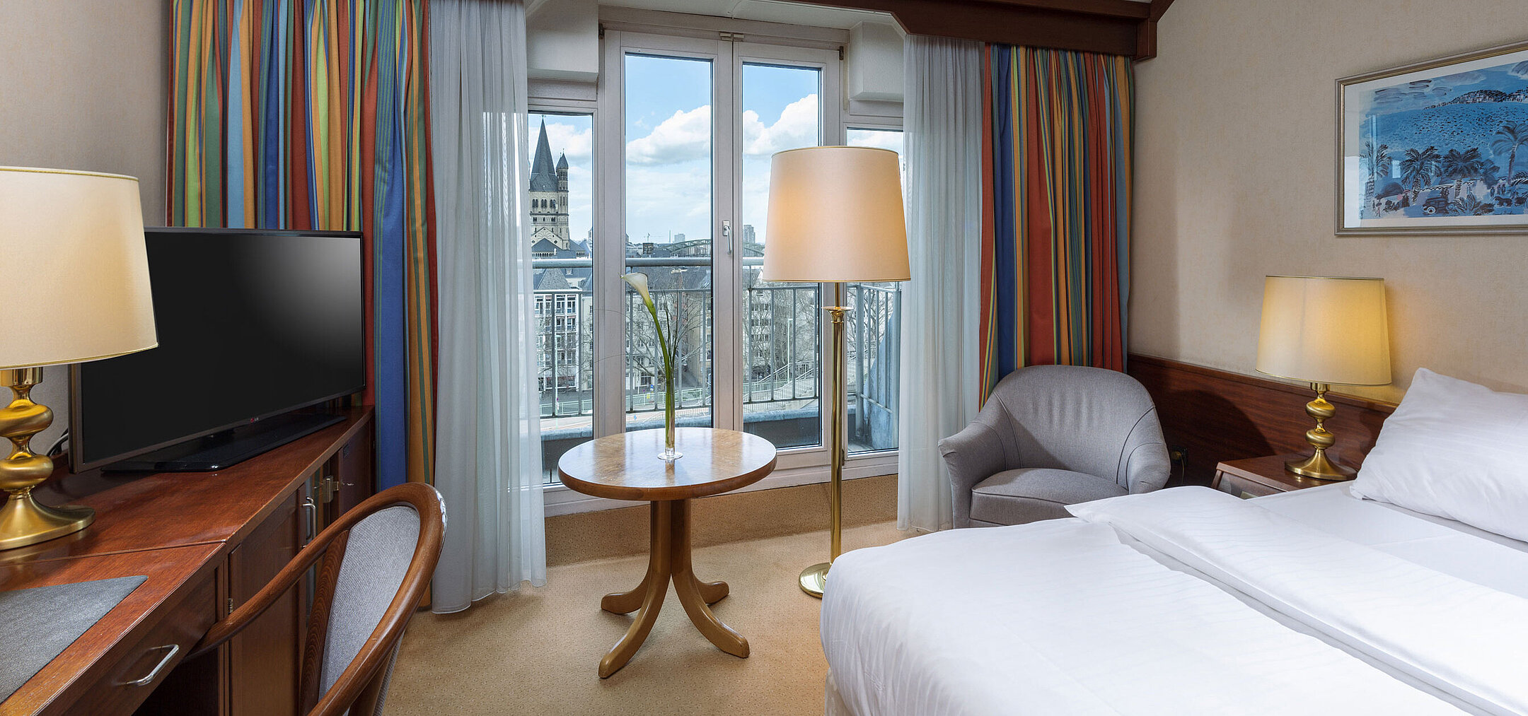 Classic room at Maritim Hotel Cologne with a double bed, desk, and view of the Rhine and historic city center.