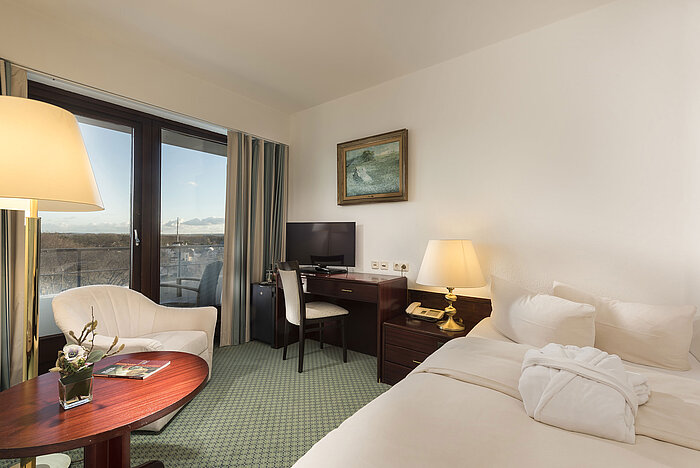 Bright single room at Maritim Seehotel Timmendorfer Strand with balcony, desk, cozy seating, and sea view.