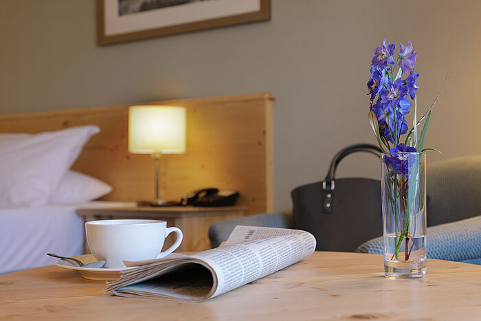 Cup of coffee, newspaper and flower on table in Maritim Hotel Titisee room
