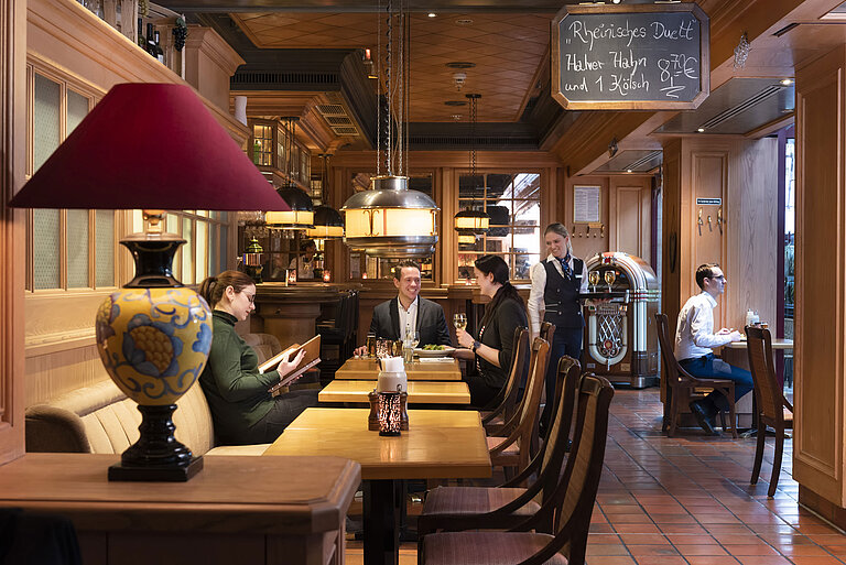Guests at "Kölsche Stuff" enjoy food and drinks in a cozy ambiance with rustic decor.