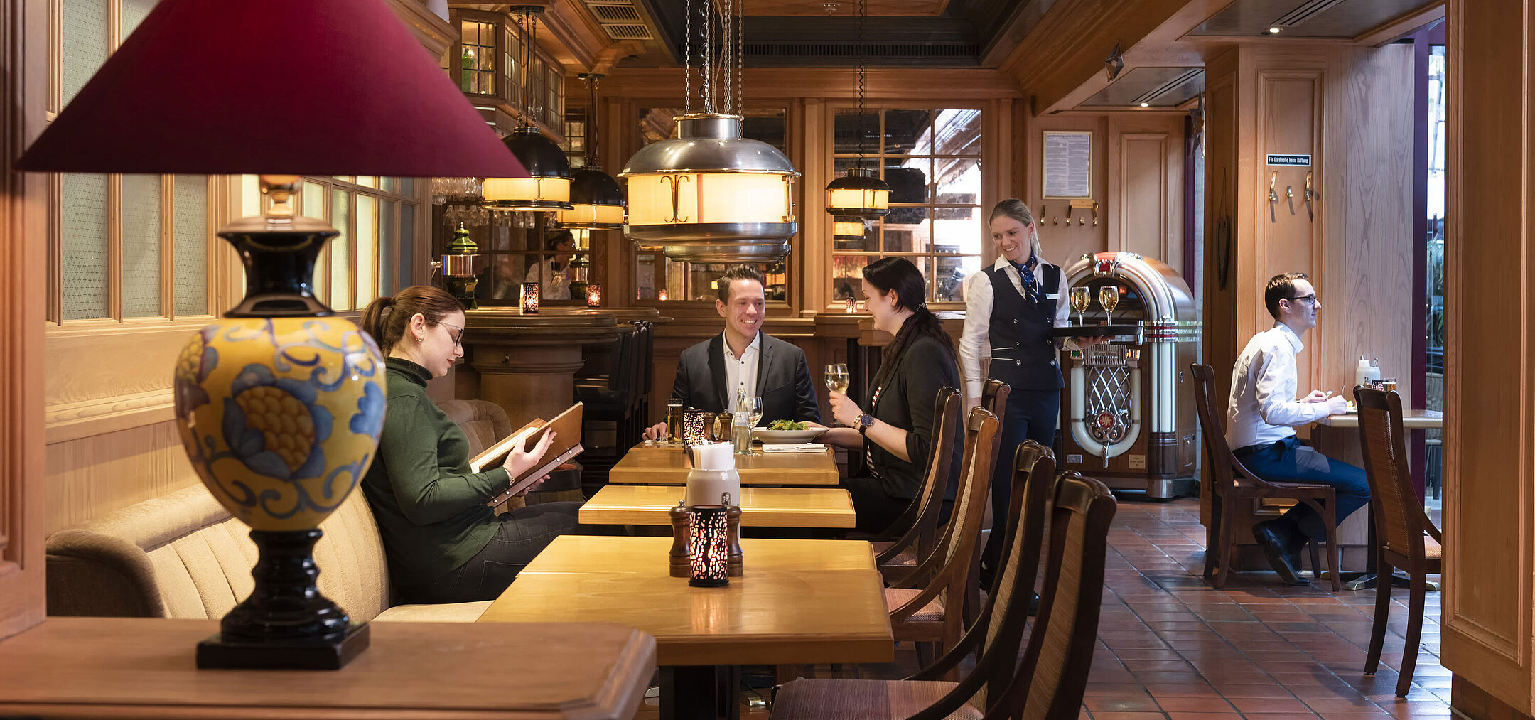 Guests at "Kölsche Stuff" enjoy food and drinks in a cozy ambiance with rustic decor.