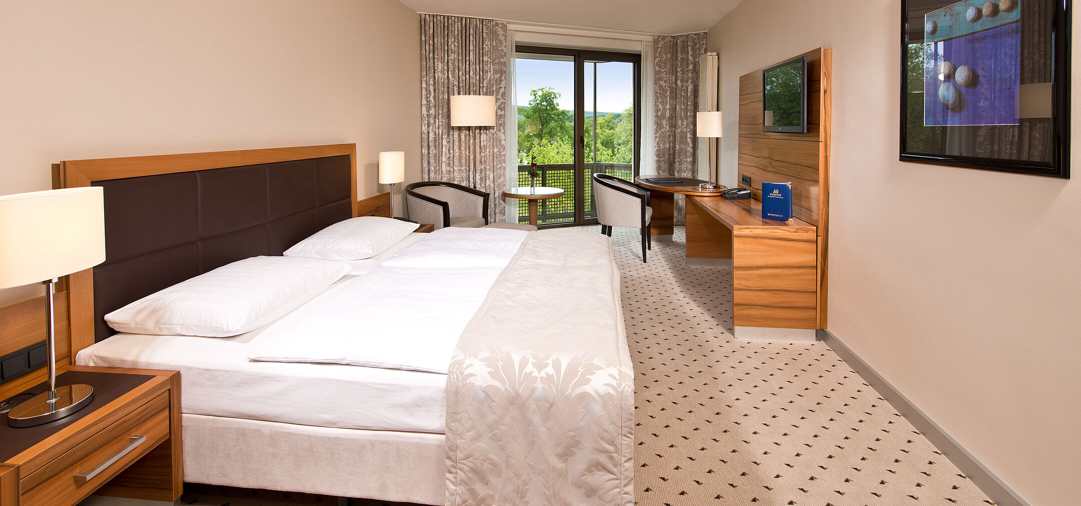 Bright room at Maritim Hotel Bad Homburg with cozy bed, desk, and balcony with green view.