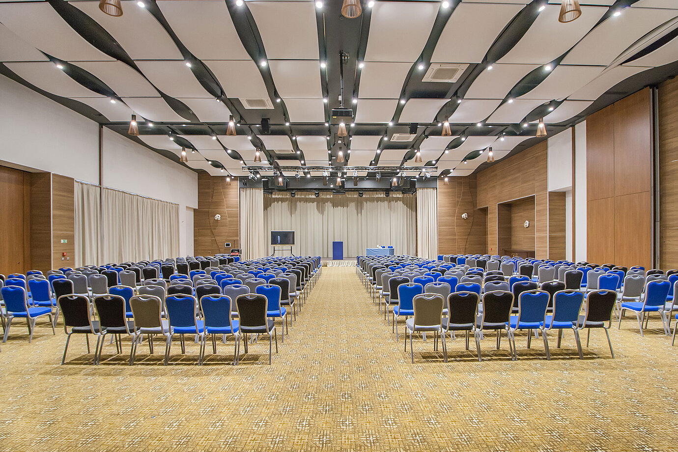 Large conference hall with many rows of chairs, stage and modern lighting for events