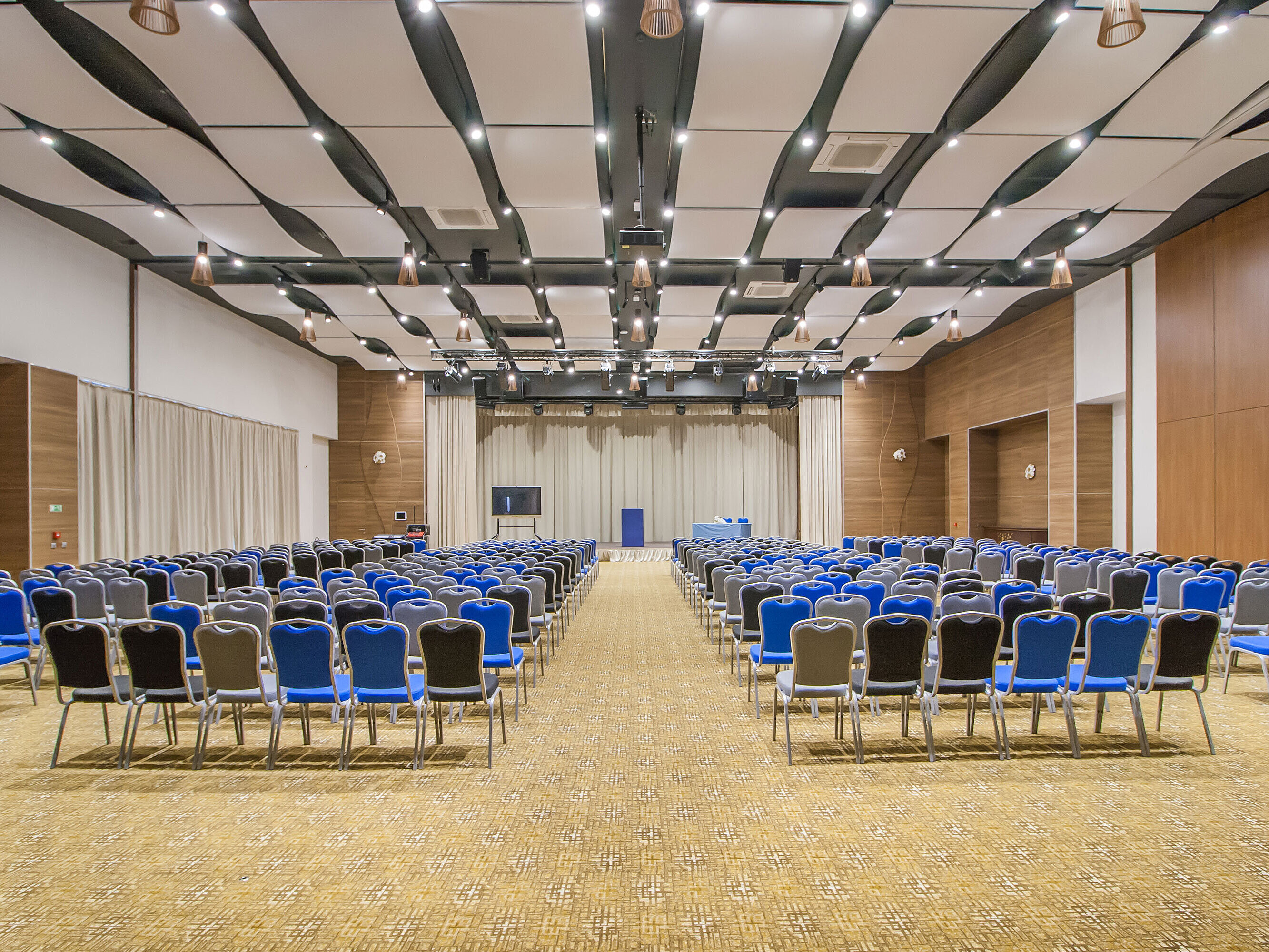 Large conference hall with many rows of chairs, stage and modern lighting for events