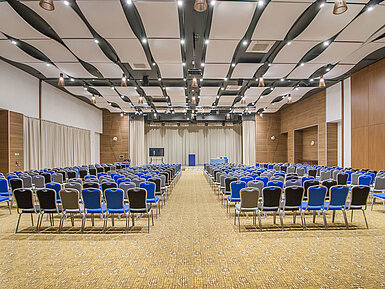 Large conference hall with many rows of chairs, stage and modern lighting for events