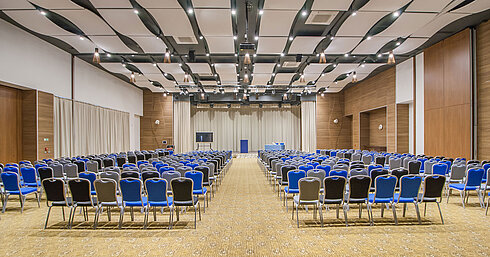 Large conference hall with many rows of chairs, stage and modern lighting for events