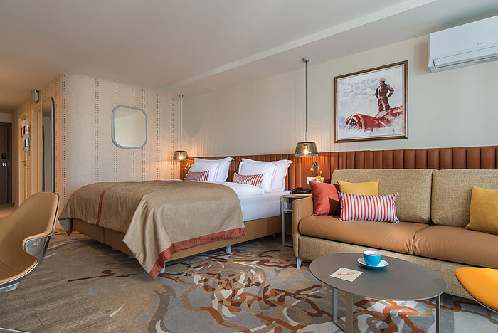 Modern room at Maritim Hotel Amelia with large bed, cosy sofa and warm colour accents