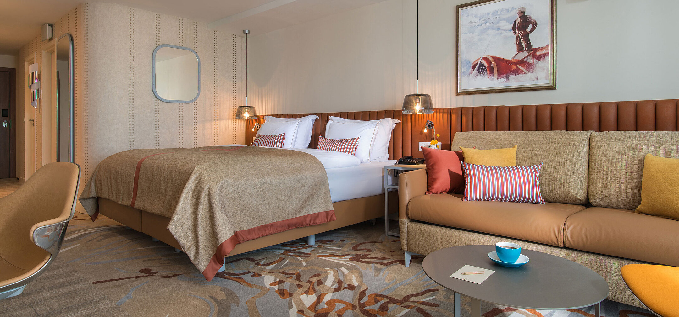 Modern room at Maritim Hotel Amelia with large bed, cosy sofa and warm colour accents