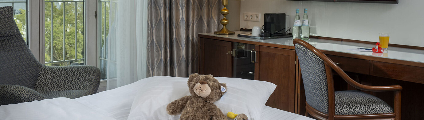 Family room at the Maritim Hotel Cologne with TV, cozy stuffed animals on the bed, and a view of the Rhine.