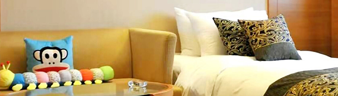 配備舒適沙發、裝飾抱枕、玻璃咖啡桌及舒適床鋪的酒店客房，讓您享受放鬆的住宿體驗