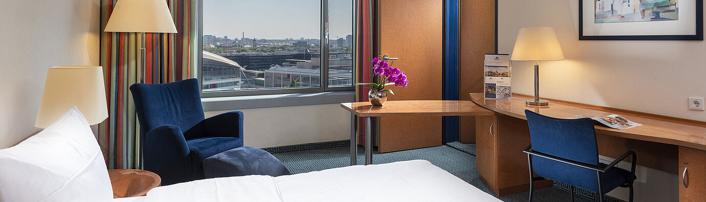 Comfort family room at Maritim Hotel Frankfurt with double bed, desk, colorful curtains, and city view.