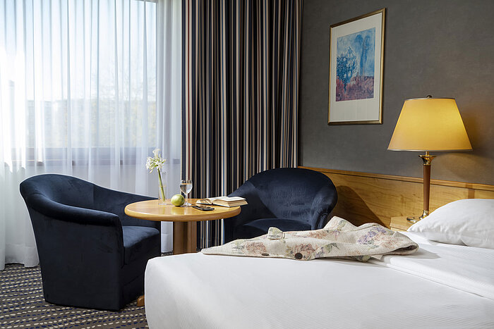Seating area in hotel room with table, book, glass of water, and apple, perfect for relaxing