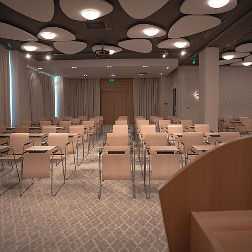 Modern conference room with row seating, bright lighting and stylish acoustic ceiling panels