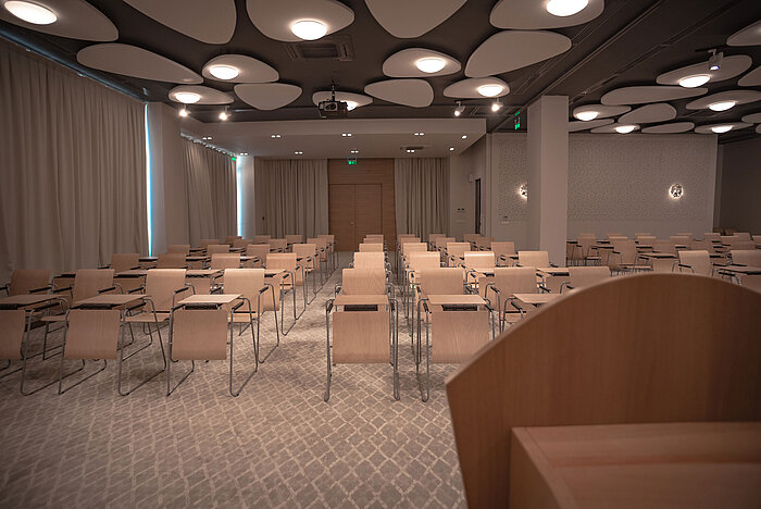 Modern conference room with row seating, bright lighting and stylish acoustic ceiling panels