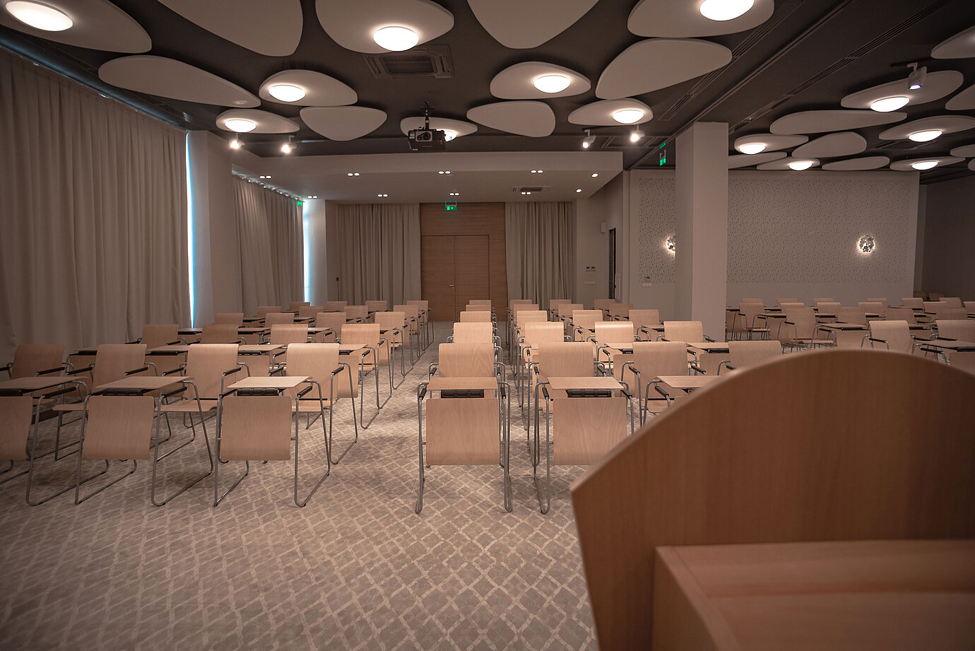 Modern conference room with row seating, bright lighting and stylish acoustic ceiling panels