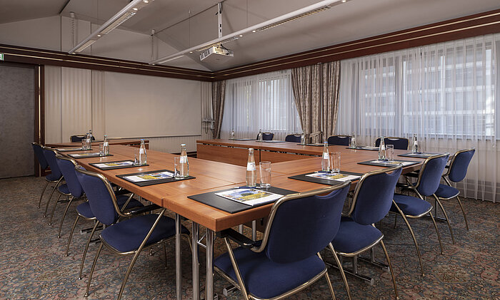Modern conference room at the Maritim Hotel Magdeburg with U-shaped seating, natural light, and high-quality equipment.