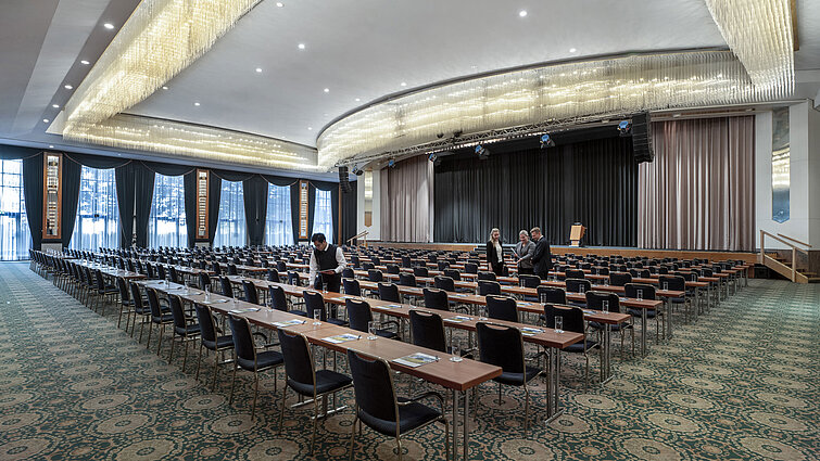 Magnificent hall at the Maritim Hotel Magdeburg with a stage, row seating, and luxurious chandelier.