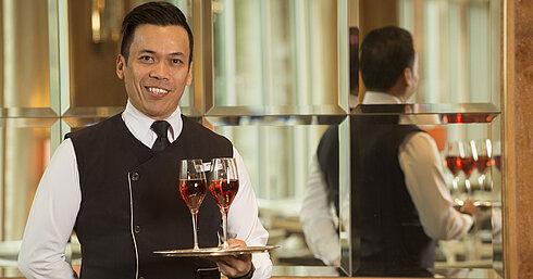 Waiter with two glasses of rosé wine on a silver tray at Maritim Hotel Stuttgart, friendly and professional