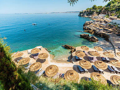 Beach area with sun umbrellas and loungers at Maritim Resort Marina Bay overlooking the turquoise sea