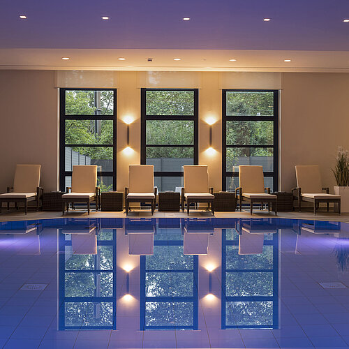 Pool area at Maritim Hotel Bonn with stylish loungers and calming lighting for ultimate relaxation.