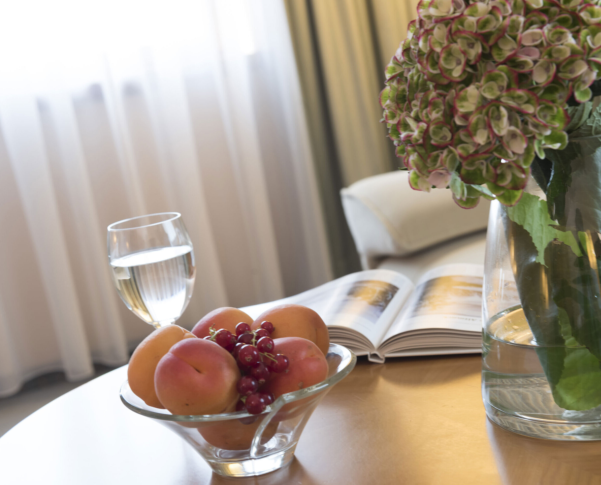 Glass of water, fruit bowl and hydrangea vase on the table at Maritim Hotel Magdeburg