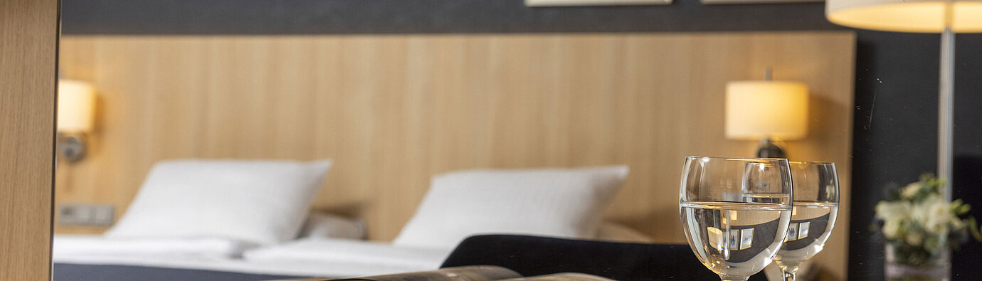 Cozy comfort room at Maritim Hotel Würzburg with mirror, open coffee-table book and water glasses