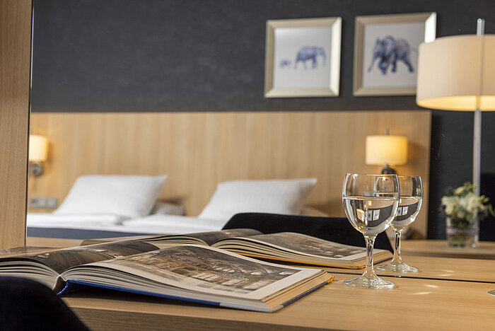 Cozy comfort room at Maritim Hotel Würzburg with mirror, open coffee-table book and water glasses