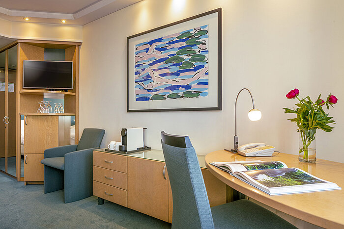 Modernly furnished Superior room at Maritim proArte Hotel Berlin with desk, artwork, armchair, and coffee machine.