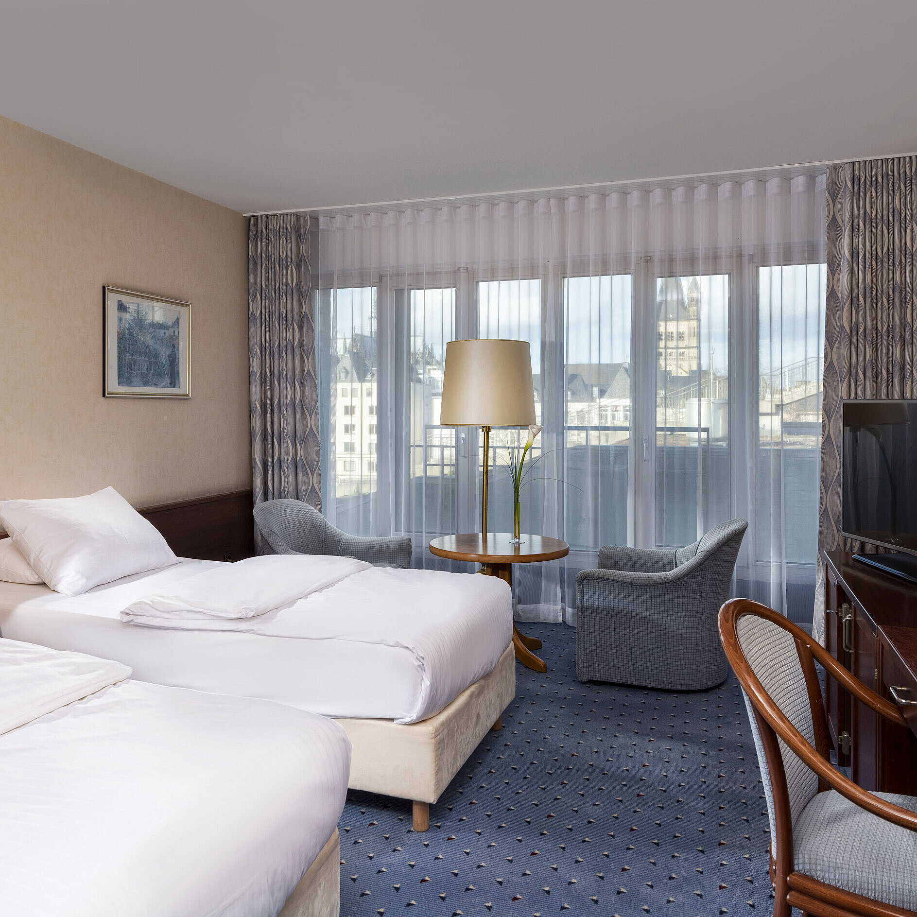 Standard Twin Room at Maritim Hotel Cologne with two beds, seating area, desk, flat-screen TV, and large windows.