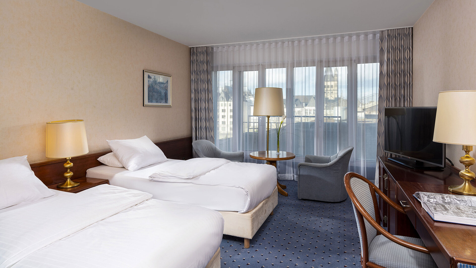 Standard Twin Room at Maritim Hotel Cologne with two beds, seating area, desk, flat-screen TV, and large windows.