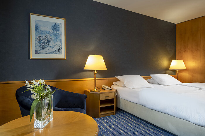 Hotel room with double bed, cozy seating area, and flowers on the table, ideal atmosphere for relaxation