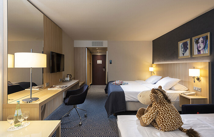 Comfort family room at Maritim Hotel Würzburg with extra bed, plush giraffe and board game