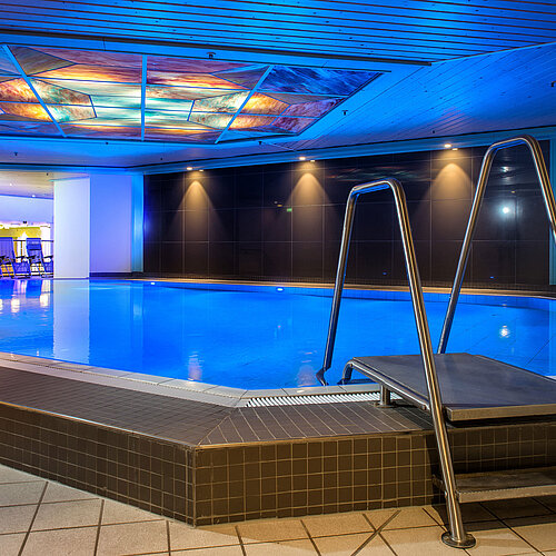 The illuminated indoor pool at Maritim Hotel, inviting relaxation and recreation.
