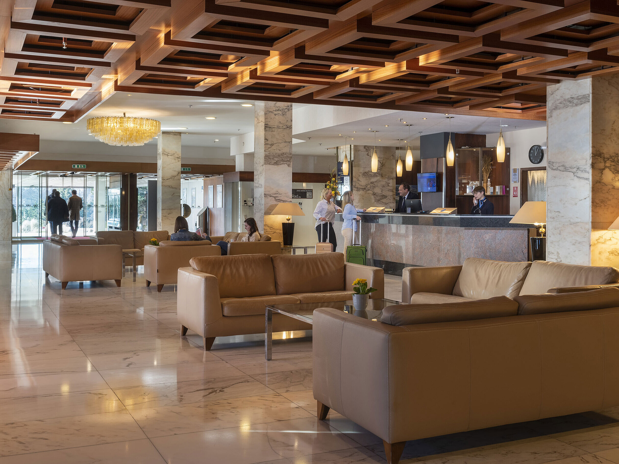 Spacious lobby with marble floor, leather sofas and reception area at Maritim Hotel Travemünde