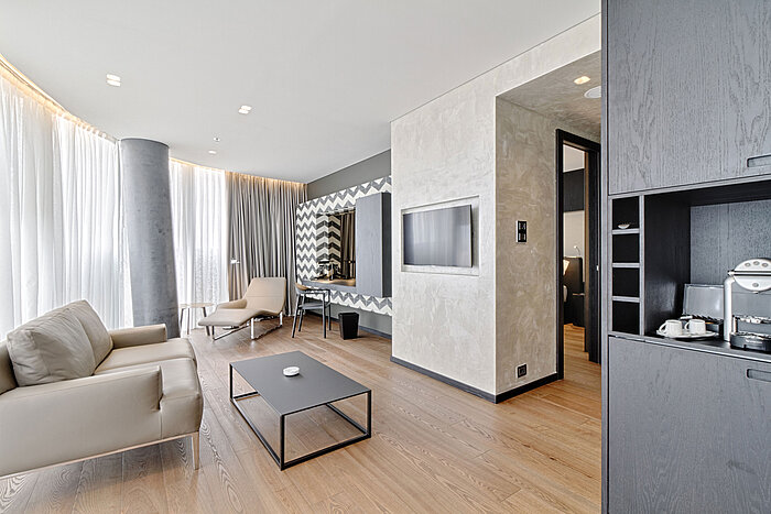 Lounge with sofa, TV, designer mirror and lounger at Maritim Hotel Plaza Tirana with natural light