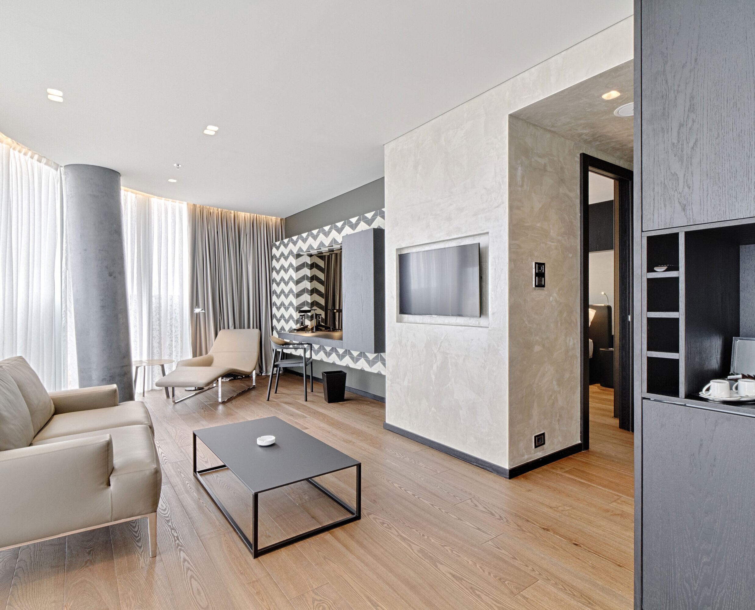 Lounge with sofa, TV, designer mirror and lounger at Maritim Hotel Plaza Tirana with natural light