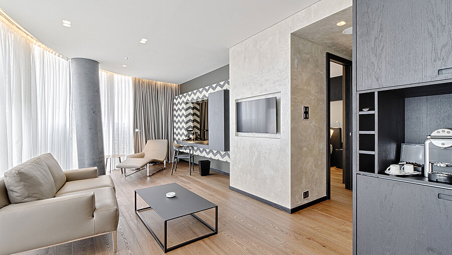 Lounge with sofa, TV, designer mirror and lounger at Maritim Hotel Plaza Tirana with natural light